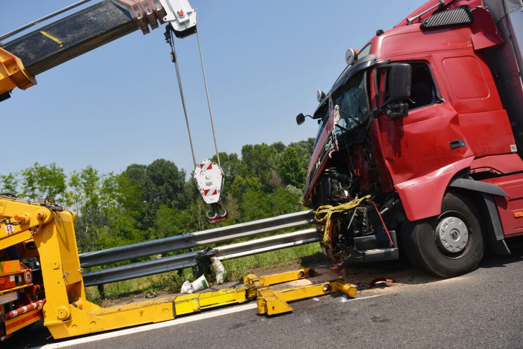 Accident on road involving semi truck being pickup up by tow vehicle