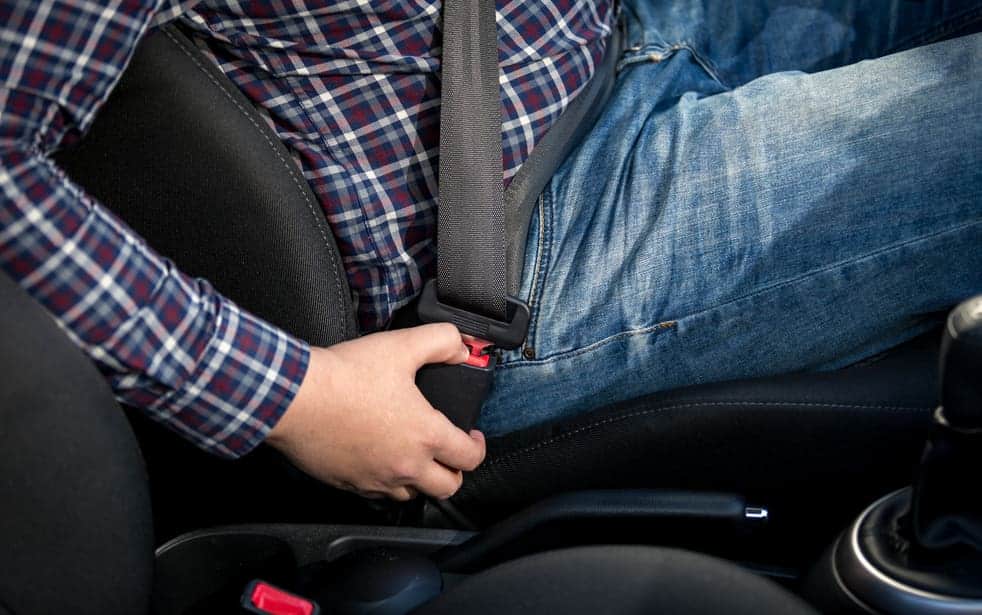 Closeup photo of man seating on drivers seat and fastening belt